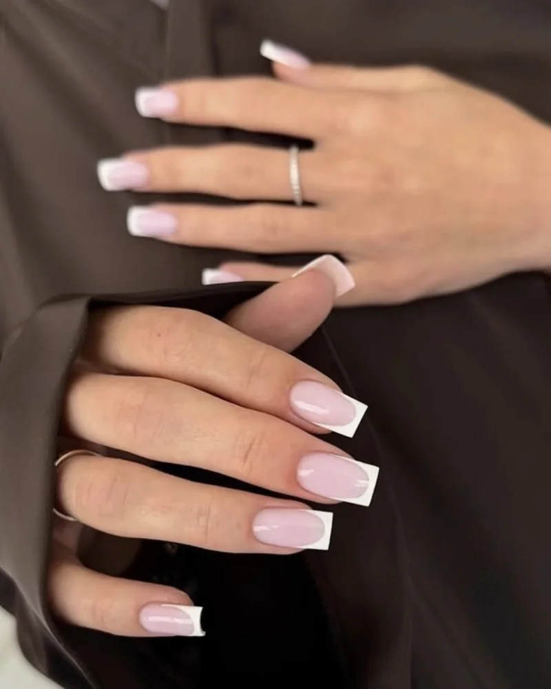 French manucure sur ongles longs carrés, posés sur un tissu brun