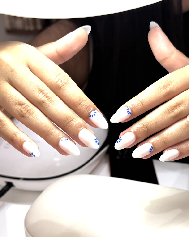 Ongles blancs avec un nail art de petites fleurs bleues
