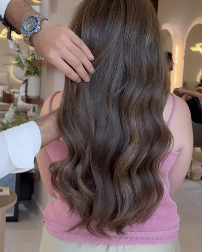 Brushing wavy sur cheveux châtains mi-longs, vus de dos dans le salon