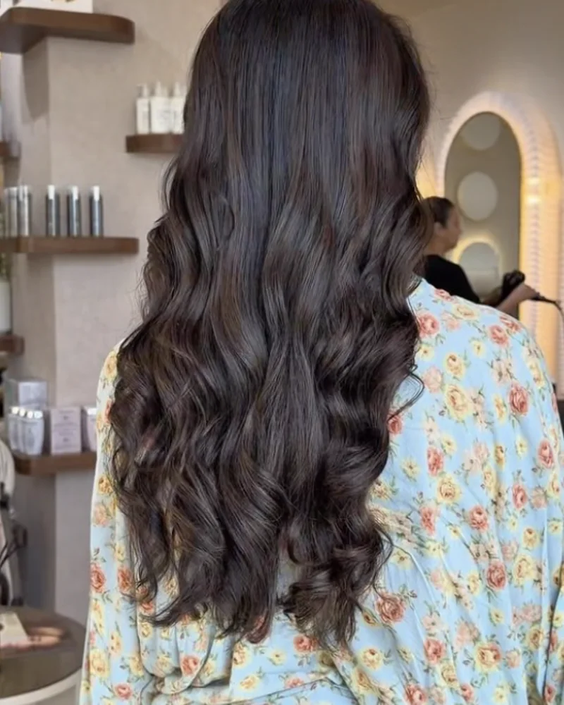 Cheveux bruns bouclés coiffés au salon, vus de dos