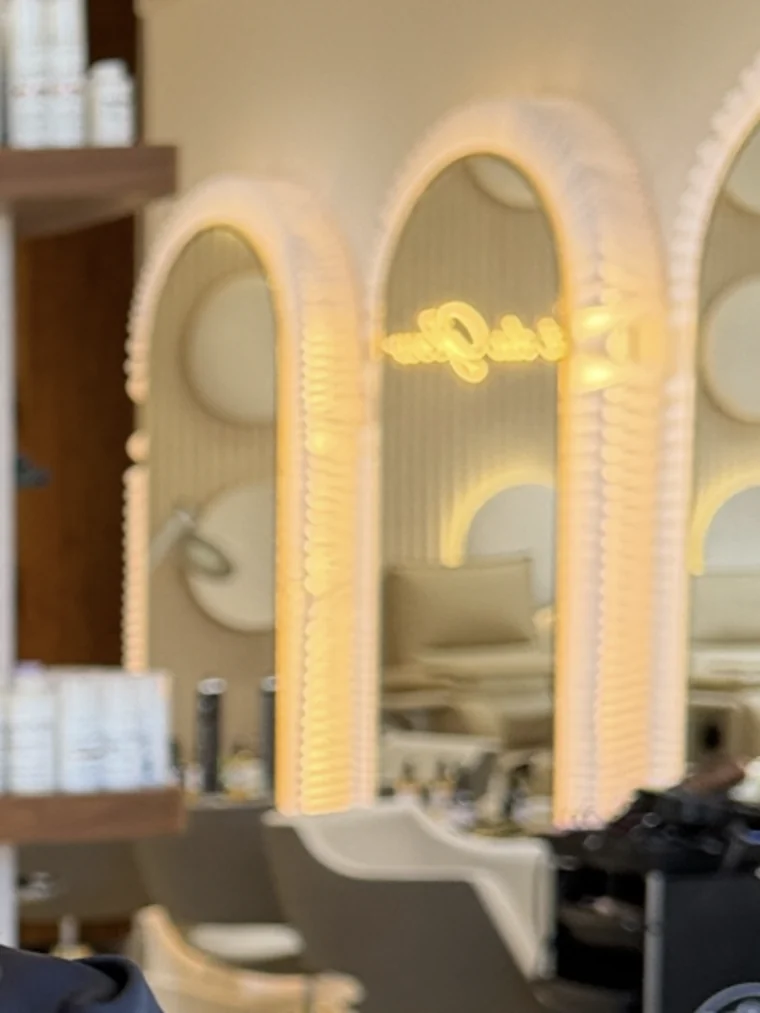 Les miroirs en arche rétroéclairés du salon, avec les étagères de produits et les fauteuils
