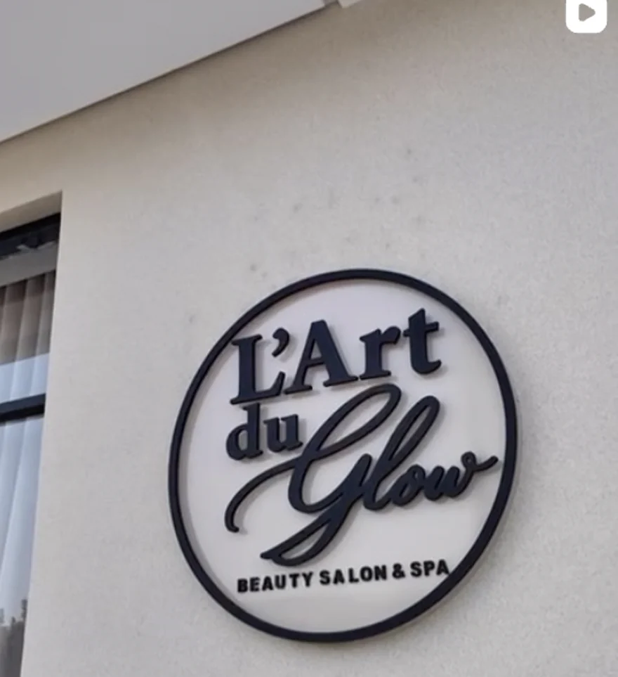 L'enseigne ronde L'Art du Glow, Beauty Salon et Spa, fixée sur le mur du centre